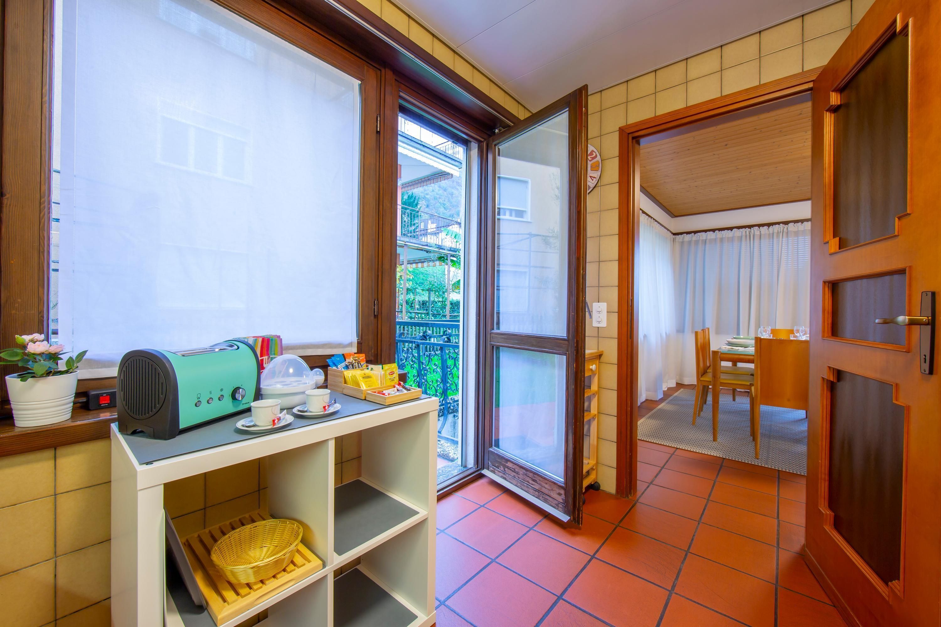 A compact kitchen with a toaster, a small table, and a window with a view of a balcony.