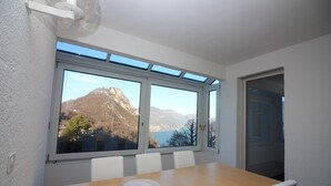 Ein Essbereich mit Holztisch, weißen Stühlen und Bergblick durch große Fenster.