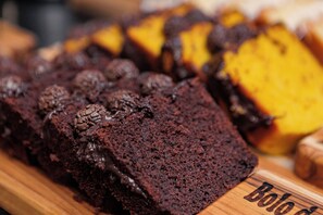 A loaf of chocolate cake with a wooden cutting board that has the name "Bob" engraved on it.