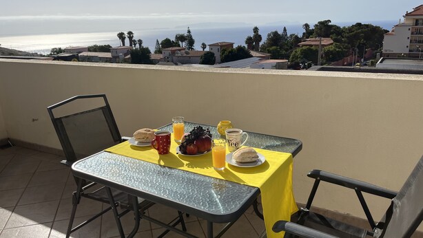 Une table dressée avec des aliments pour le petit-déjeuner, placée sur un balcon donnant sur la mer.