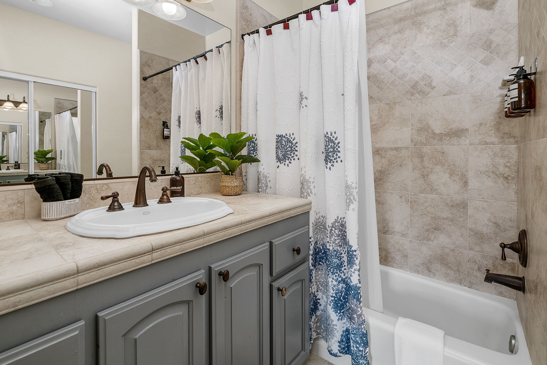 Une salle de bain avec un lavabo, un miroir et un rideau de douche.