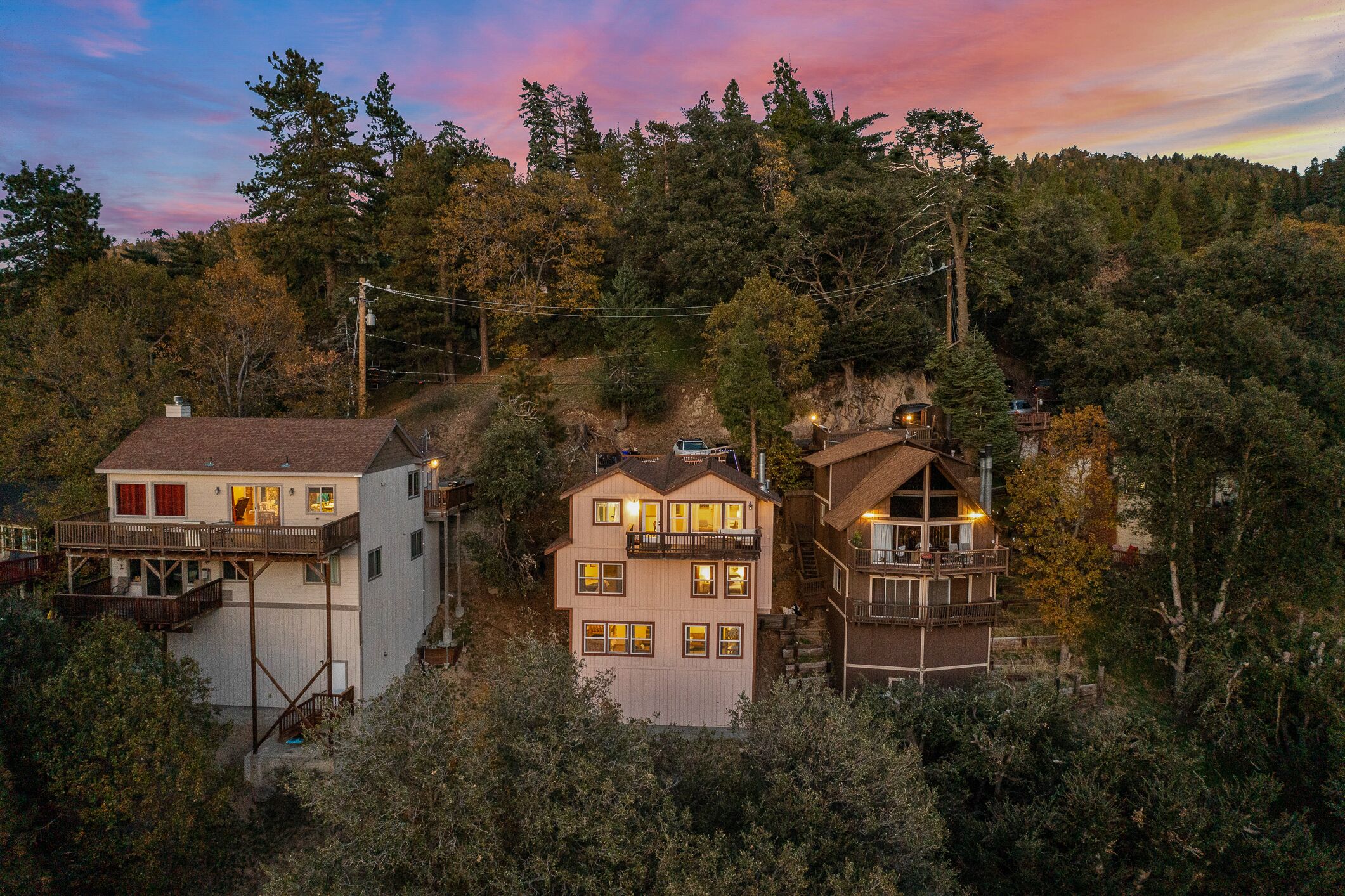 Une maison à plusieurs étages dotée d’un balcon, entourée d’une forêt dense.