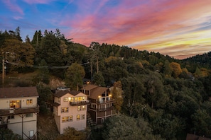 A multi-story building with multiple balconies and a view of a forested hillside.