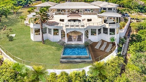Una casa grande y lujosa con piscina, varias terrazas y un jardín cuidado.