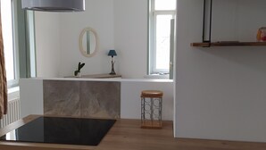 A modern kitchen with a built-in stove, oven, and a hanging light fixture. - Le Sunny - Spacious, renovated duplex apartment (Outreau)