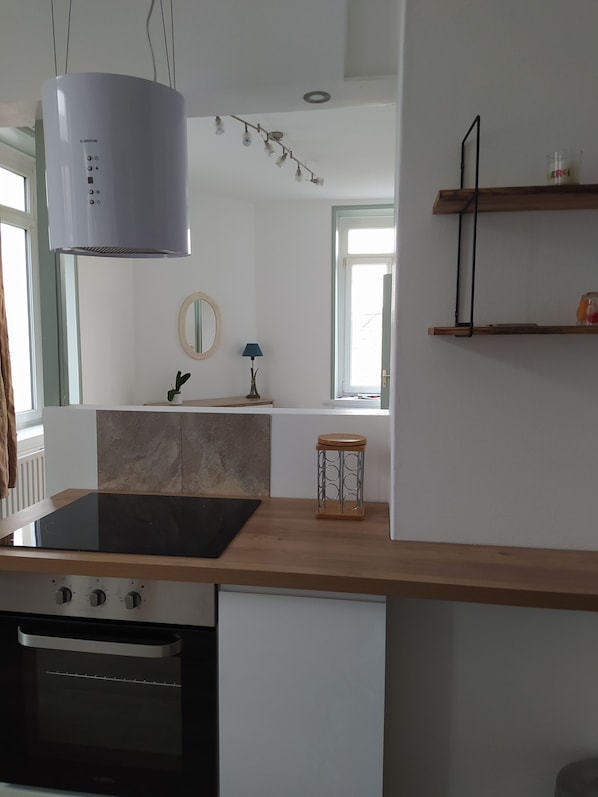 Una cucina moderna con piano cottura integrato, forno e lampada a sospensione.