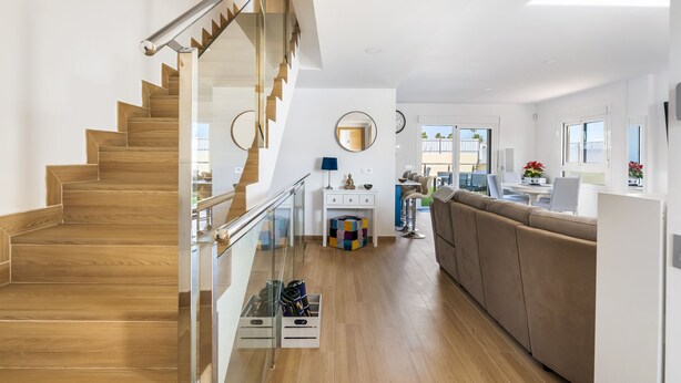Ein modernes Interieur mit einer Holztreppe, einer Couch, einem Essbereich und einer Küche.