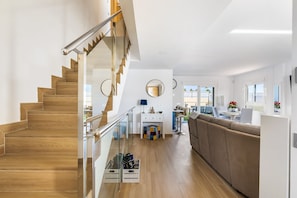 Ein modernes Interieur mit einer Holztreppe, einer Couch, einem Essbereich und einer Küche.