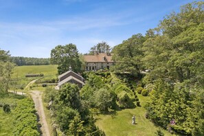 A large estate with a main house and a smaller building, surrounded by lush greenery and a well-maintained lawn. - Stunning Historic Maine Stone Castle (Bath)