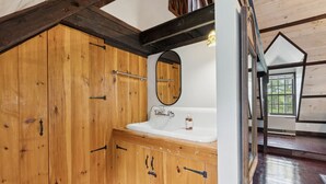 A wooden bathroom with a large mirror, a sink, and a window. - Stunning Historic Maine Stone Castle (Bath)