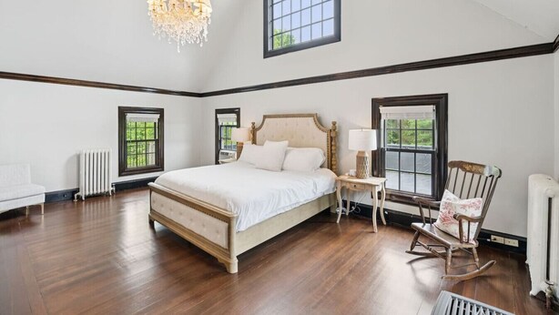 A spacious bedroom with a large bed, a chandelier, and multiple windows. - Stunning Historic Maine Stone Castle (Bath)