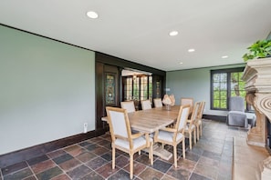 A dining area with a large wooden table, six chairs, and a fireplace. - Stunning Historic Maine Stone Castle (Bath)