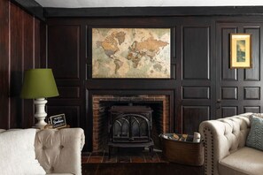 A room with a fireplace, a world map on the wall, a lamp, and a sofa. - Stunning Historic Maine Stone Castle (Bath)