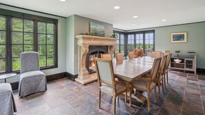 A dining room with a fireplace, large windows, and a view of the outdoors. - Stunning Historic Maine Stone Castle (Bath)