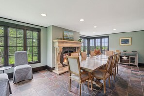 A dining room with a fireplace, large windows, and a view of the outdoors. - Stunning Historic Maine Stone Castle (Bath)