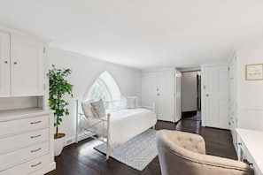 A bedroom with a bed, a chair, a dresser, a window, and a door. - Stunning Historic Maine Stone Castle (Bath)