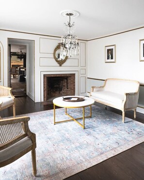 A living room with a fireplace, a chandelier, and a white sofa. - Stunning Historic Maine Stone Castle (Bath)