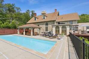 A pool area with lounge chairs and a gazebo, surrounded by stone walls and a wooden deck. - Stunning Historic Maine Stone Castle (Bath)