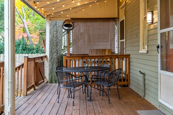 Une terrasse en bois avec une table ronde et des chaises, une clôture en bois et une cloche.