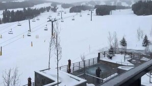 Ein verschneiter Skihang mit Skiliften und einer Person, die auf einer Plattform steht.