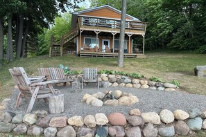 Une cabane dotée d’une terrasse, d’un espace salon extérieur et d’un foyer entouré de rochers.