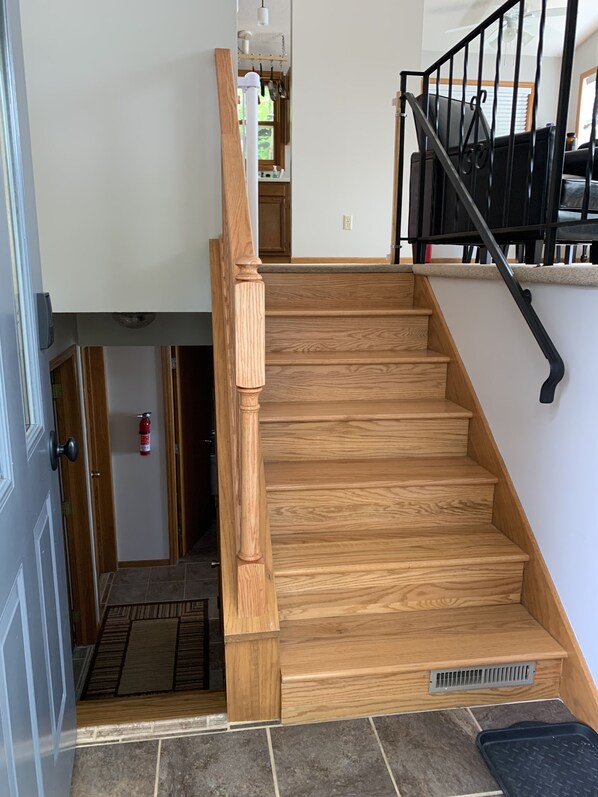 Una escalera de madera con barandal negro que sube a un segundo piso.