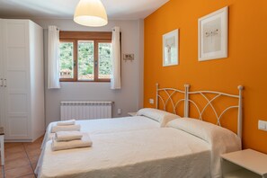 Cozy retreat with a large bed, white headboard, and two pillows, set against a vibrant wall.