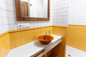 Bathroom features a white countertop, brown sink, and a bathtub.