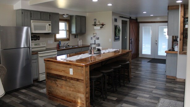 A modern kitchen with a central island, stainless steel appliances, and wooden flooring. - Ohio Street Retreat-hot tub, pool, massage chair (Prairie du Chien)