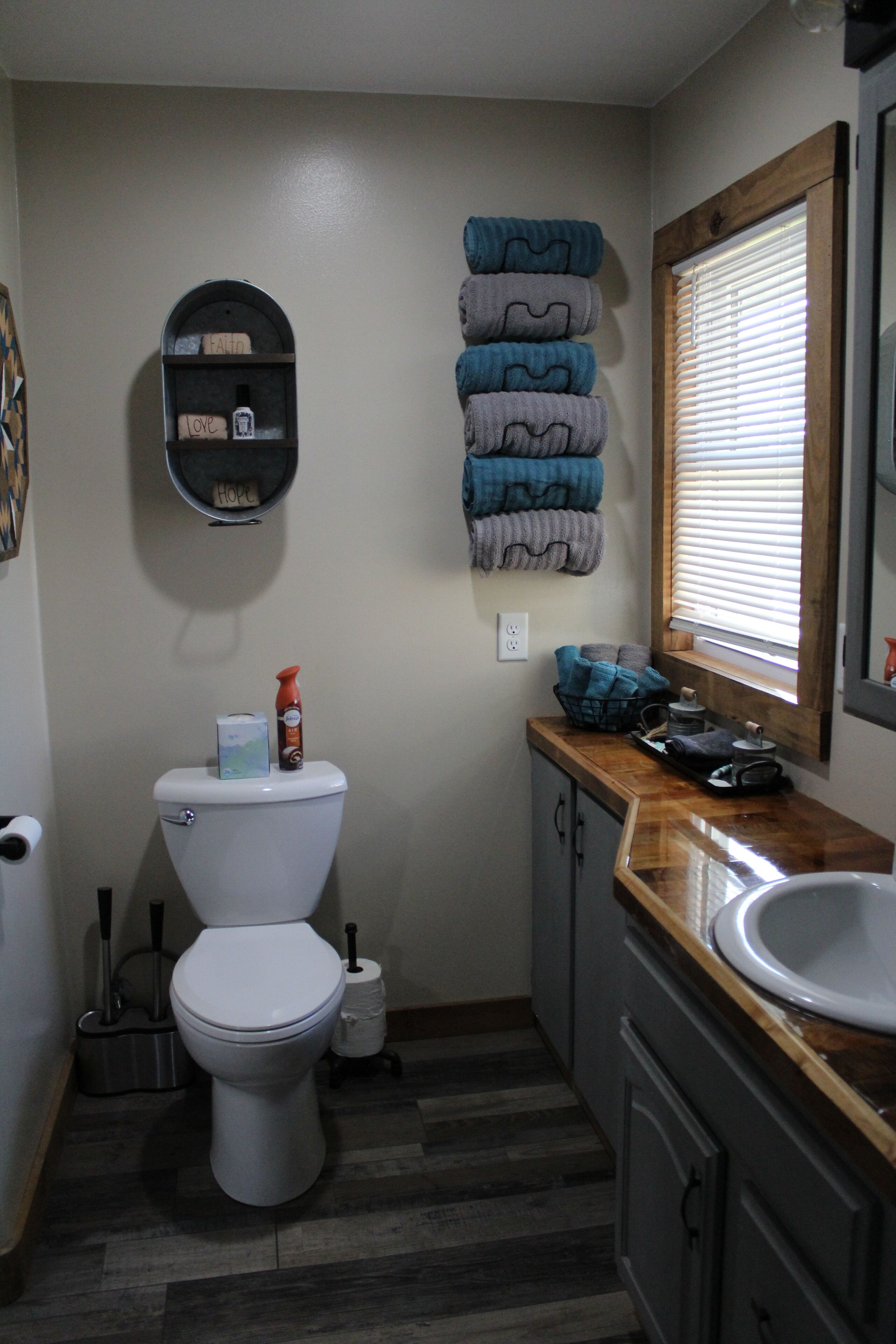 A compact bathroom with a toilet, a sink, and a window with blinds.