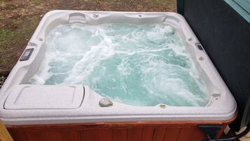 A hot tub with a control panel, surrounded by a wooden deck.