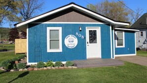 A small, single-story building with a blue exterior and a white door, labeled "Ohio Street 808" and "Retreat." - Ohio Street Retreat-hot tub, pool, massage chair (Prairie du Chien)
