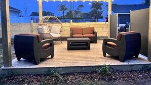 Eine Terrasse im Freien mit Korbmöbeln, einer Hängematte und Lichterketten.