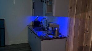 Eine kleine Küche mit Spüle, Kaffeemaschine und Mikrowelle.