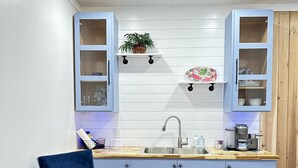 Eine moderne Küche mit Holzarbeitsplatte, Spüle und Schränken. Auf der Arbeitsfläche steht ein blauer Stuhl und ein Blumentopf.