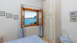 Ein Schlafzimmer mit großem Fenster, einem Bett, einem Kleiderschrank und einem Sessel.