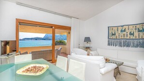 Ein Zimmer mit Glastisch, weißem Sofa und Meerblick.
