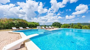 Ein klares, blaues Schwimmbecken mit Liegestühlen und einer Ziegelterrasse.