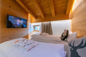 A wooden-paneled room with two beds, a television, and a window with curtains. - Lucia in Livigno With 2 Bedrooms and 2 Bathrooms (Livigno)