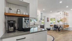 Eine moderne Küche mit Kaffeemaschine, integriertem Wasserspender und einem Essbereich mit Hängesessel.