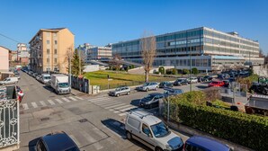 En modern stadsgata med en blandning av affärs- och bostadshus, ett övergångsställe och parkerade fordon.