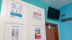 Ett rum med en tv som är monterad på väggen, en dörr med en skylt och inramade affischer på väggen.