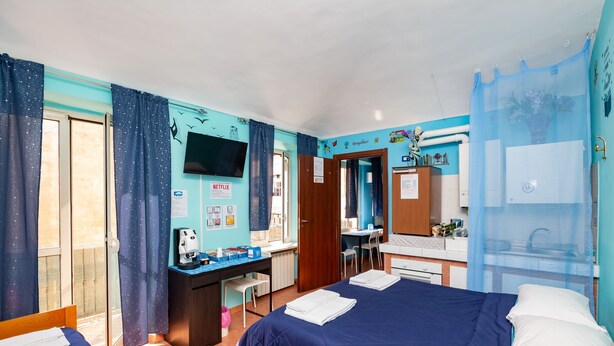 Ett hotellrum med två sängar, ett skrivbord, en stol, en TV och en duschhörna.