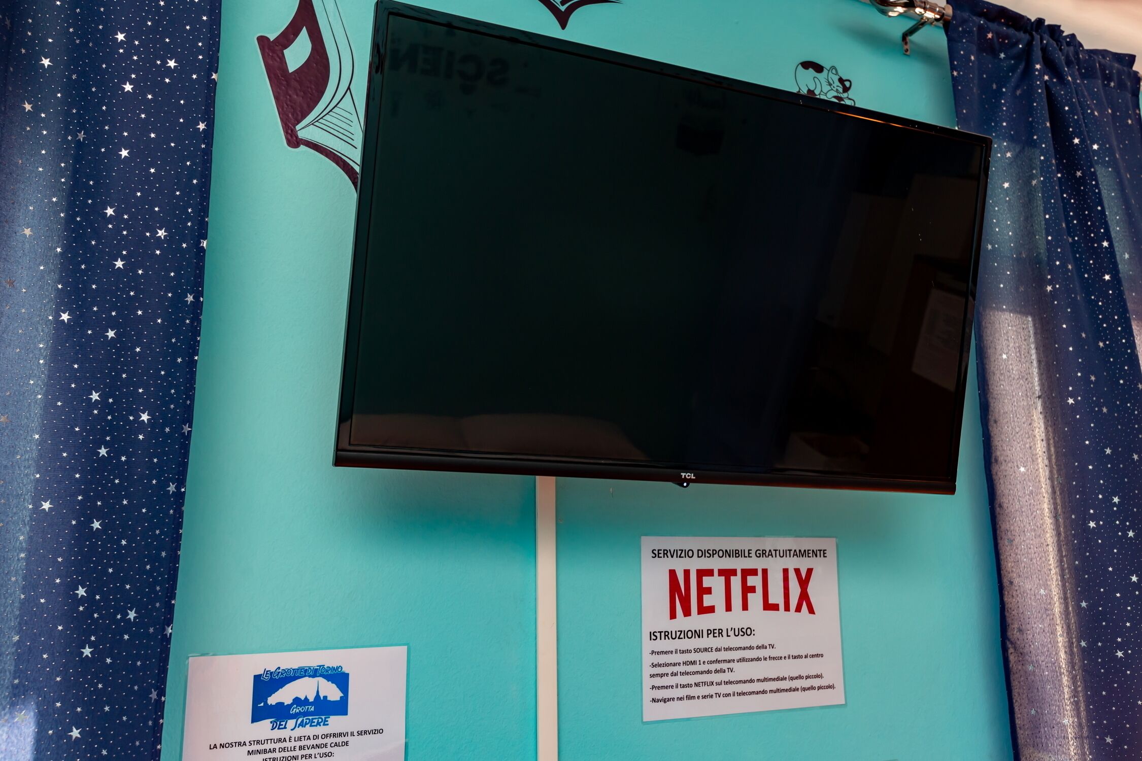 A wall with a mounted television, a sign for free Netflix service, and a logo for 'Le Giornale del Mare'.