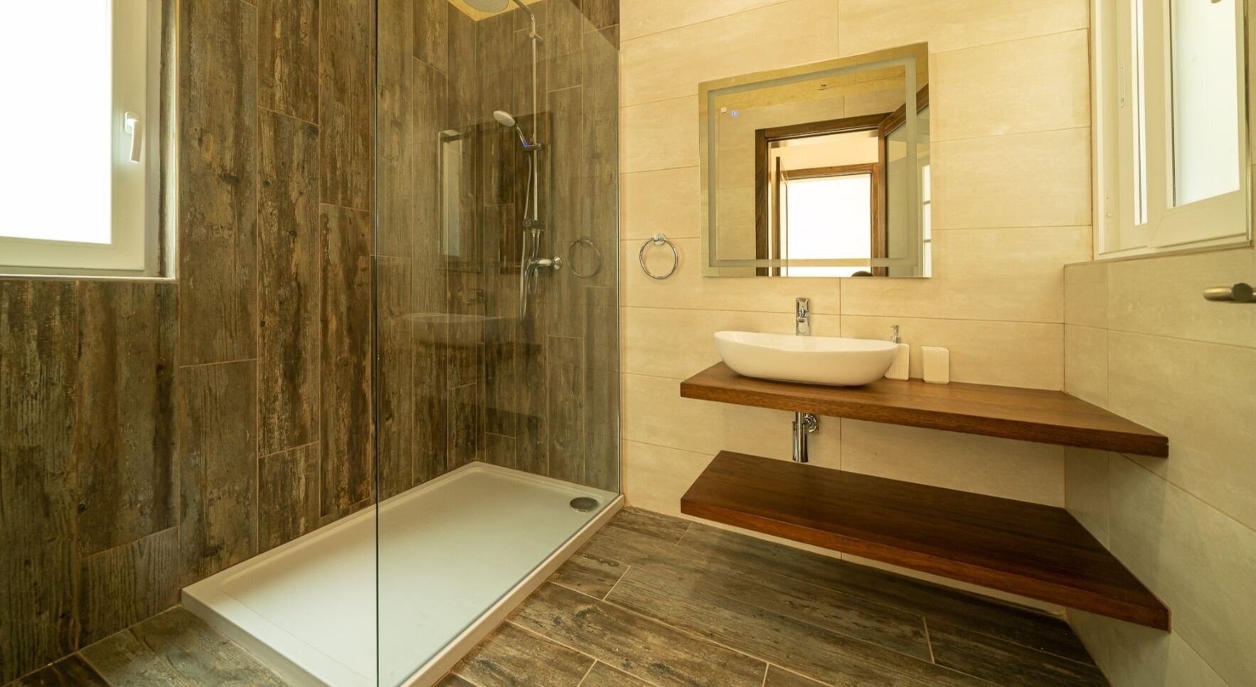 A modern bathroom with a glass-enclosed shower, a wooden vanity with a vessel sink, and a mirror above the sink.