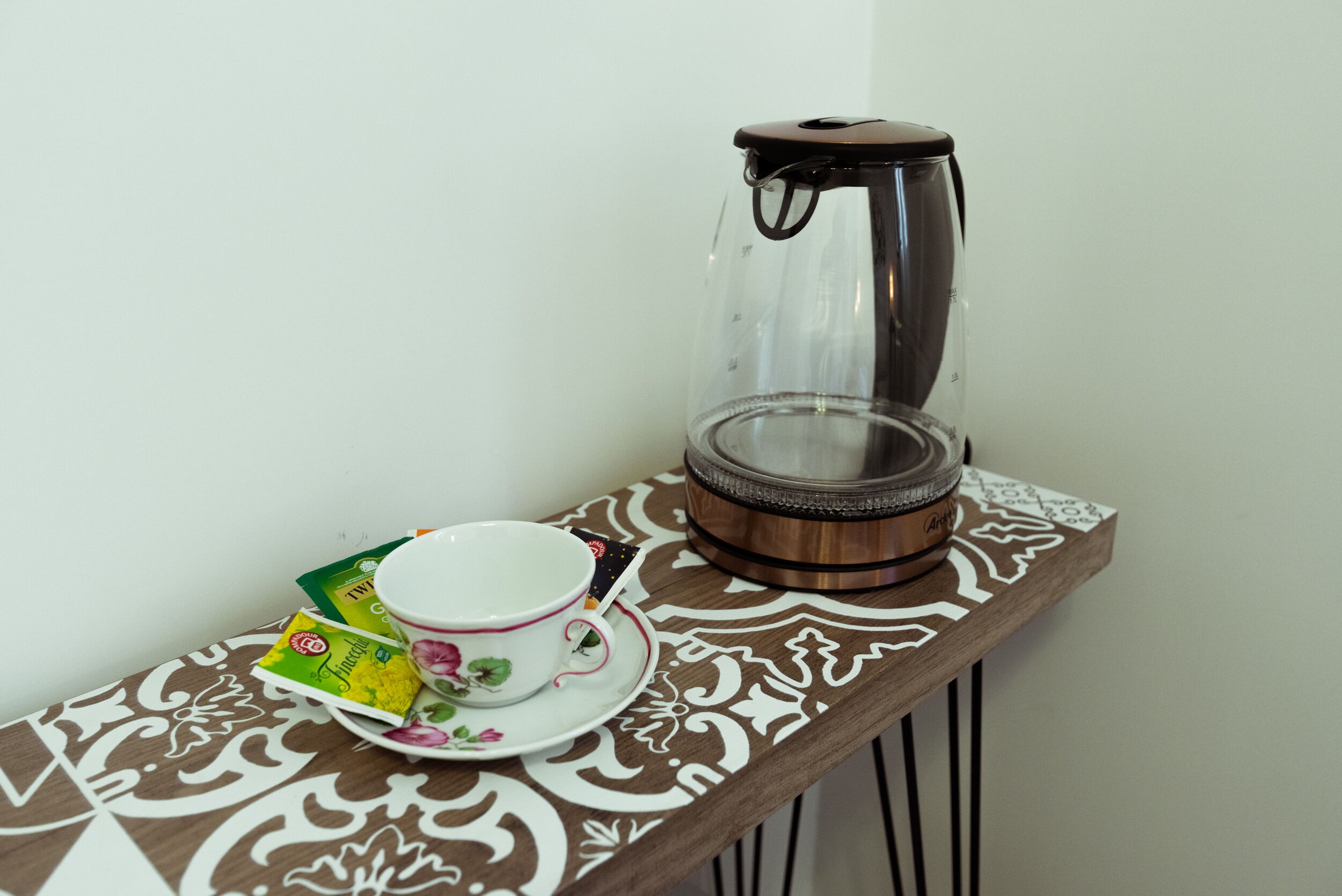 A table with a teapot, a cup, and tea packets.