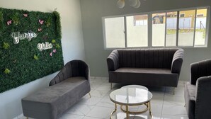Un área de estar moderna con una pared verde, dos sofás y una mesa de centro redonda.