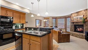 Una cocina moderna con armarios de madera, una estufa negra y una chimenea de piedra.