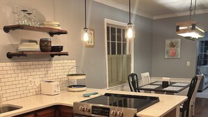 A kitchen with a built-in oven, a sink, and a countertop. There are hanging lights, a window with shutters, and a dining area with chairs. - Charming home in downtown Camden (Camden)