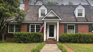 A two-story brick house with a front porch, a central door, and an American flag. - Charming home in downtown Camden (Camden)